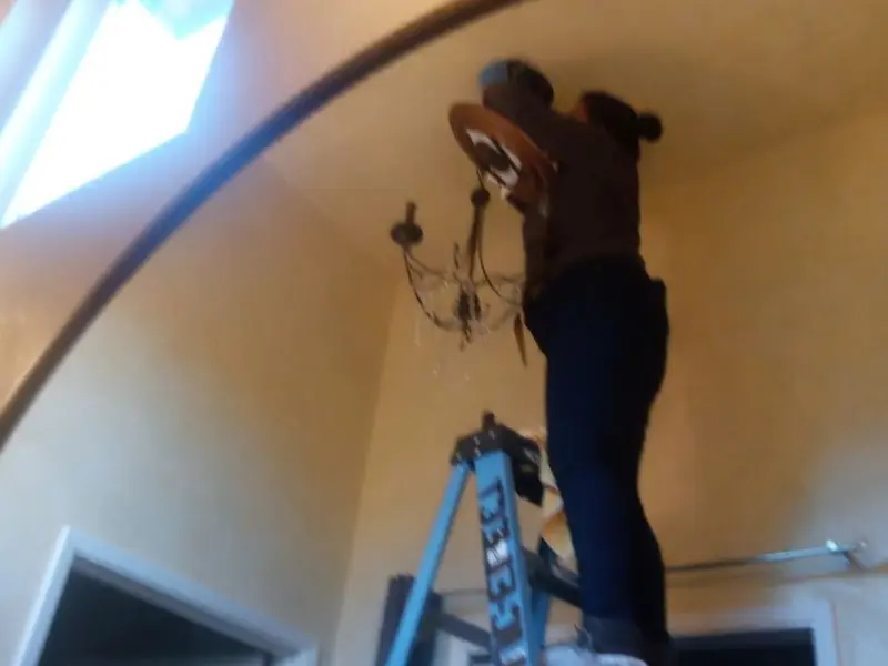 Electrician installing a chandelier in a Raymondville residence